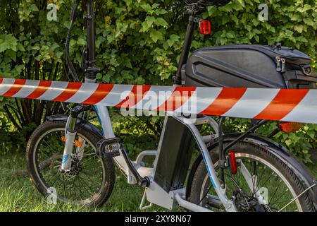 Un accident sur un vélo électrique, la zone sécurisée par la police avec du ruban protecteur rouge et blanc Banque D'Images