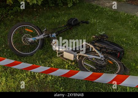 Un accident sur un vélo électrique, la zone sécurisée par la police avec du ruban protecteur rouge et blanc Banque D'Images