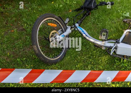 Un accident sur un vélo électrique, la zone sécurisée par la police avec du ruban protecteur rouge et blanc Banque D'Images