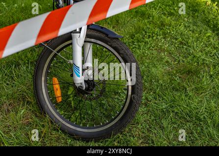 Un accident sur un vélo électrique, la zone sécurisée par la police avec du ruban protecteur rouge et blanc Banque D'Images