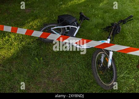 Un accident sur un vélo électrique, la zone sécurisée par la police avec du ruban protecteur rouge et blanc Banque D'Images