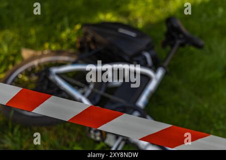 Un accident sur un vélo électrique, la zone sécurisée par la police avec du ruban protecteur rouge et blanc Banque D'Images