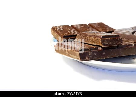 Gros plan d'une barre de chocolat cassée en morceaux disposés sur une soucoupe. Vue latérale. Banque D'Images