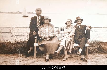 Palic, Subotica, Yougoslavie (maintenant Serbie) - 1930 : groupe de personnes, deux couples, assis sur le banc au bord du lac Banque D'Images