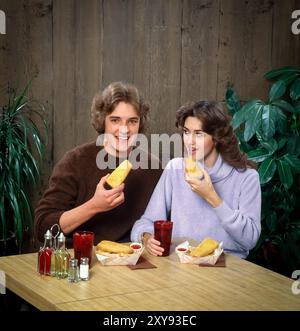 'Scène gastronomique rétro avec un intérieur aux couleurs vives, les clients, les modèles posent naturellement, soulignant l'ambiance sociale, confortable et nostalgique. Banque D'Images