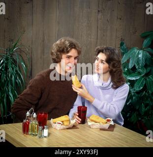 'Scène gastronomique rétro avec un intérieur aux couleurs vives, les clients, les modèles posent naturellement, soulignant l'ambiance sociale, confortable et nostalgique. Banque D'Images