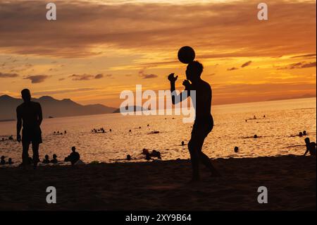 Silhouettes de joueurs de balle hommes asiatiques jouant traditionnel de football de plage sepak takraw par la mer en été au lever du soleil Banque D'Images