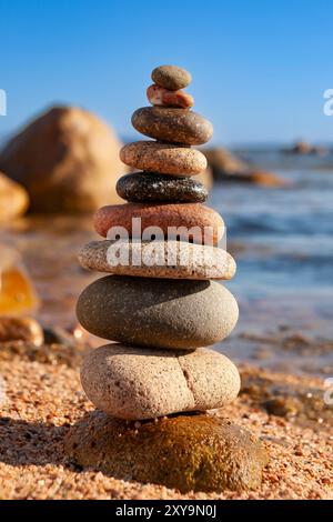 Zen comme des pierres. Pierres zen empilées. Pierres plates empilées au bord d'une plage, engorgées par les vagues d'eau. Symbole de méditation du bouddhisme de la paix. Banque D'Images