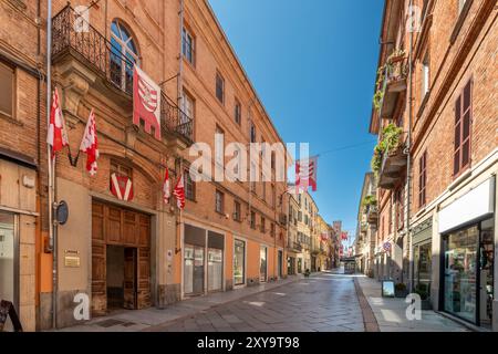 Asti, Italie - 20 août 2024 : vue sur la zone piétonne de via Vittorio Alfieri dans le centre historique de la ville, avec des bâtiments anciens et les bannières Banque D'Images