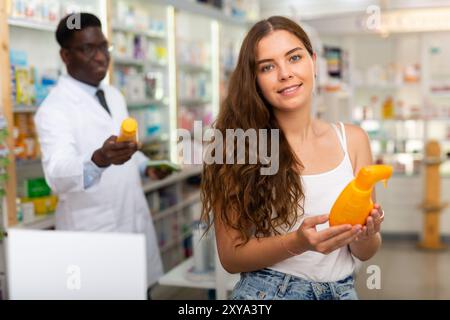 Adolescente choisissant des produits de soins capillaires en pharmacie Banque D'Images