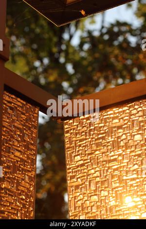 Une surface de verre texturée capte la douce lueur du coucher du soleil, avec un élément vertical aligné avec la règle des tiers. La composition joue avec lig Banque D'Images