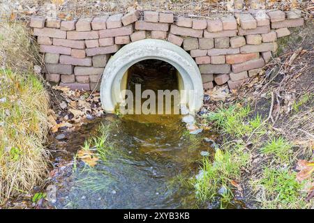 L'eau qui coule à travers ponceau en béton au fossé Banque D'Images