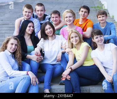 Groupe d'adolescents souriants assis à l'extérieur. Concept d'amitié Banque D'Images