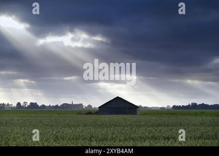 Cabane en bois au-dessus du ciel avec des rayons de soleil sur les terres agricoles Banque D'Images