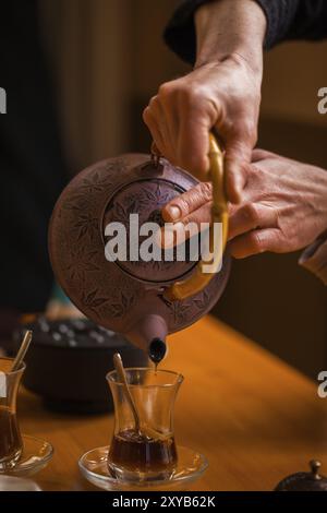 Les mains des femmes versent le thé dans un verre Banque D'Images