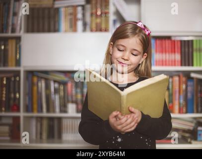 Portrait de la jolie petite lycéenne holding book et de la lecture Banque D'Images