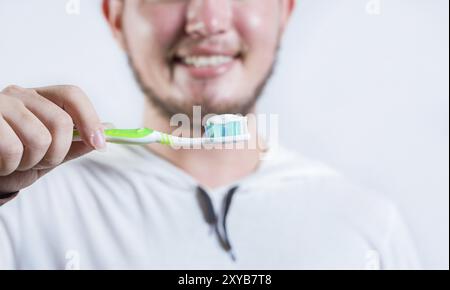 Main de l'homme montrant brosse à dents avec dentifrice isolé. Gros plan des mains tenant la brosse avec le dentifrice Banque D'Images