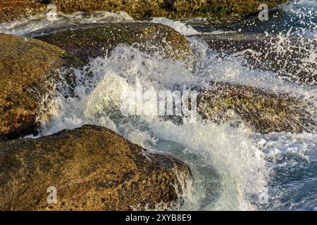 L'eau de mer éclabloussures sur les pierres sur la plage Banque D'Images