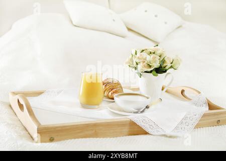 Petit-déjeuner au lit avec café, jus d'orange et un croissant sur un plateau Banque D'Images