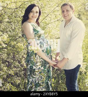 Young happy pregnant couple dans le parc printemps floraison. Portrait en extérieur Banque D'Images