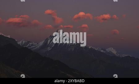 Scène de soirée dans la zone de conservation de l'Annapurna. Nuages roses au-dessus du mont Machapuchare. Vue sur le coucher du soleil depuis la colline de Muldhai Banque D'Images