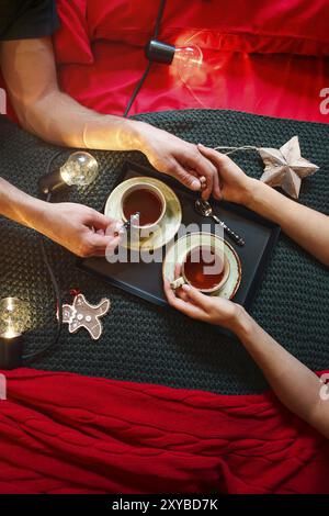 Tasse de thé dans les mains et la décoration sur le lit. Vue d'en haut. Concept d'amour Banque D'Images