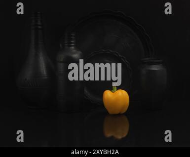 Nature morte affichant une soucoupe noire et des assiettes avec un poivron. Gros plan, prise de vue en studio. Banque D'Images