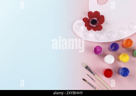 Palette de couleurs aquarelle et pinceaux sur fond bleu et rose dégradé, copie espace flatlay Banque D'Images