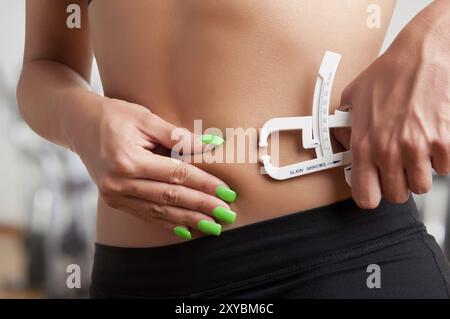 Woman measuring son corps gras avec une graisse du corps, de l'étrier dans une salle de sport Banque D'Images