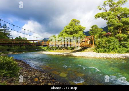 La lumière matinale orageuse dramatique ombrage la moitié du pont Kappa Bashi sur les rives de la rivière Azusa Gawa dans les Alpes japonaises village de Kamikochi, Nagano, J Banque D'Images