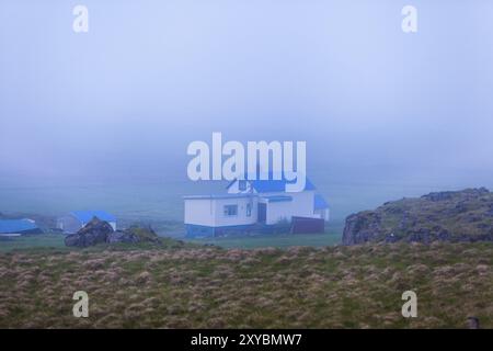 Ferme blanche solitaire buidling avec un toit bleu enveloppé de brume sur l'Islande Banque D'Images