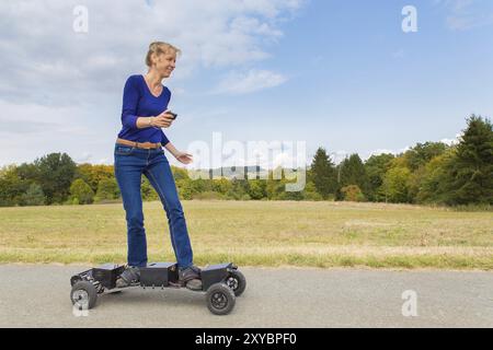 Caucasian woman rides mountainboard électrique sur route dans la nature Banque D'Images