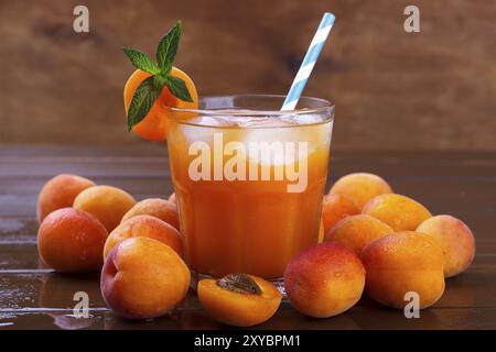 Jus d'abricot frais avec de la glace sur la vieille table en bois brun, mise au point sélective Banque D'Images