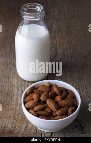 Amandes et lait d'amande dans une bouteille sur une vieille table en bois Banque D'Images