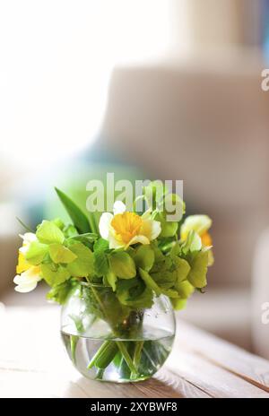 Vase rond avec eau propre et fleurs naturelles délicates placés sur la table Banque D'Images