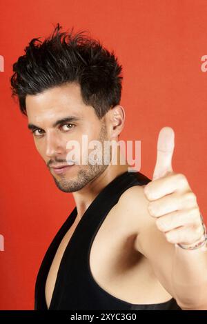 Smiling attractive 30 ans man with Thumbs up sur un fond orange Banque D'Images