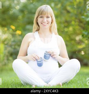 Portrait pleine longueur d'une femme enceinte heureuse tenant un bottin bleu dans les mains Banque D'Images