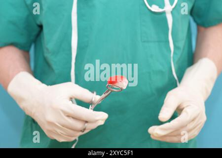 Un chirurgien qualifié tient un écouvillon d'instrument chirurgical dans une salle d'opération soigneusement préparée Banque D'Images