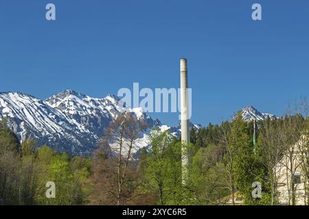 Cheminée d'usine à Fuessen am Lech devant un pic alpin Banque D'Images