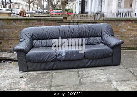 Vieux canapé en attente de collecte de meubles refusés devant la maison Banque D'Images