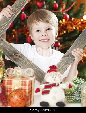 Joyeux garçon jouant contre fond de lumières de Noël Banque D'Images