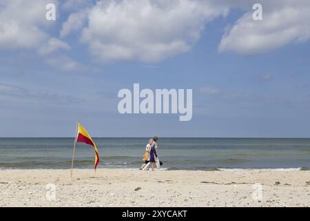 Tisvilde, Danemark, 20 juin 2016 : des gens marchent derrière le drapeau rouge et jaune de la zone de baignade à la plage de Tisvilde, en Europe Banque D'Images