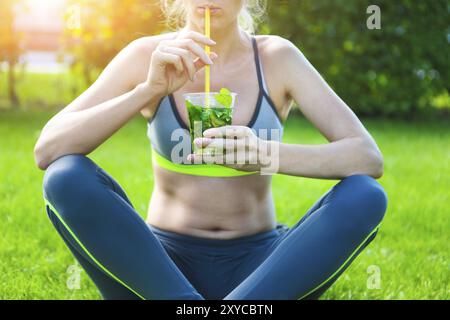 Femme buvant herbal tisane après exécution remise en forme d'entraînement sur journée d'été. Concept de remise en forme et d'un style de vie sain Banque D'Images