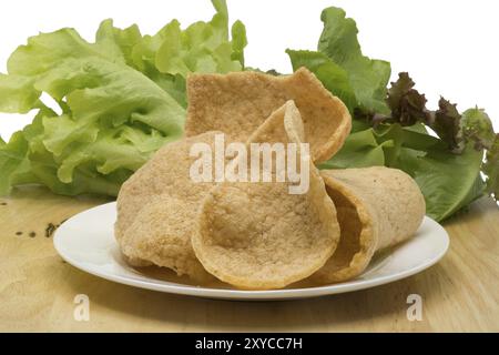 Craquelin aux crevettes et légumes dans une assiette blanche sur une planche en bois sur fond blanc Banque D'Images