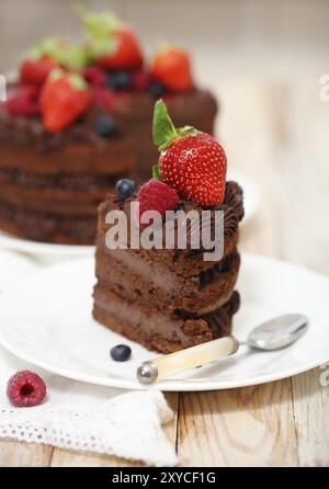 Morceau de gâteau au chocolat avec du glaçage et de Berry sur fond clair Banque D'Images