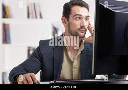 L'homme surpris en regardant un écran d'ordinateur, de penser à la tâche à accomplir Banque D'Images