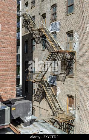 Escalier d'évasion de couleur marron dans un ancien bâtiment résidentiel en briques à Chelsea, New York, pendant la journée hivernale ensoleillée, verticale Banque D'Images