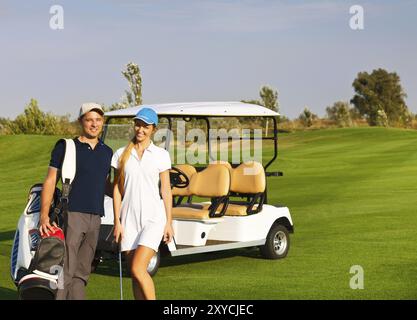 Jeune couple sportif jouer au golf sur un parcours de golf. Debout près de l'golfcar Banque D'Images