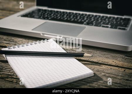 Station de travail de bureau avec ordinateur portable, portable et crayon sur une vieille table en bois Banque D'Images