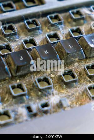 Un clavier avec beaucoup de cheveux dessus. De nombreux boutons du clavier ont été retirés, attendant d'être nettoyés. Banque D'Images